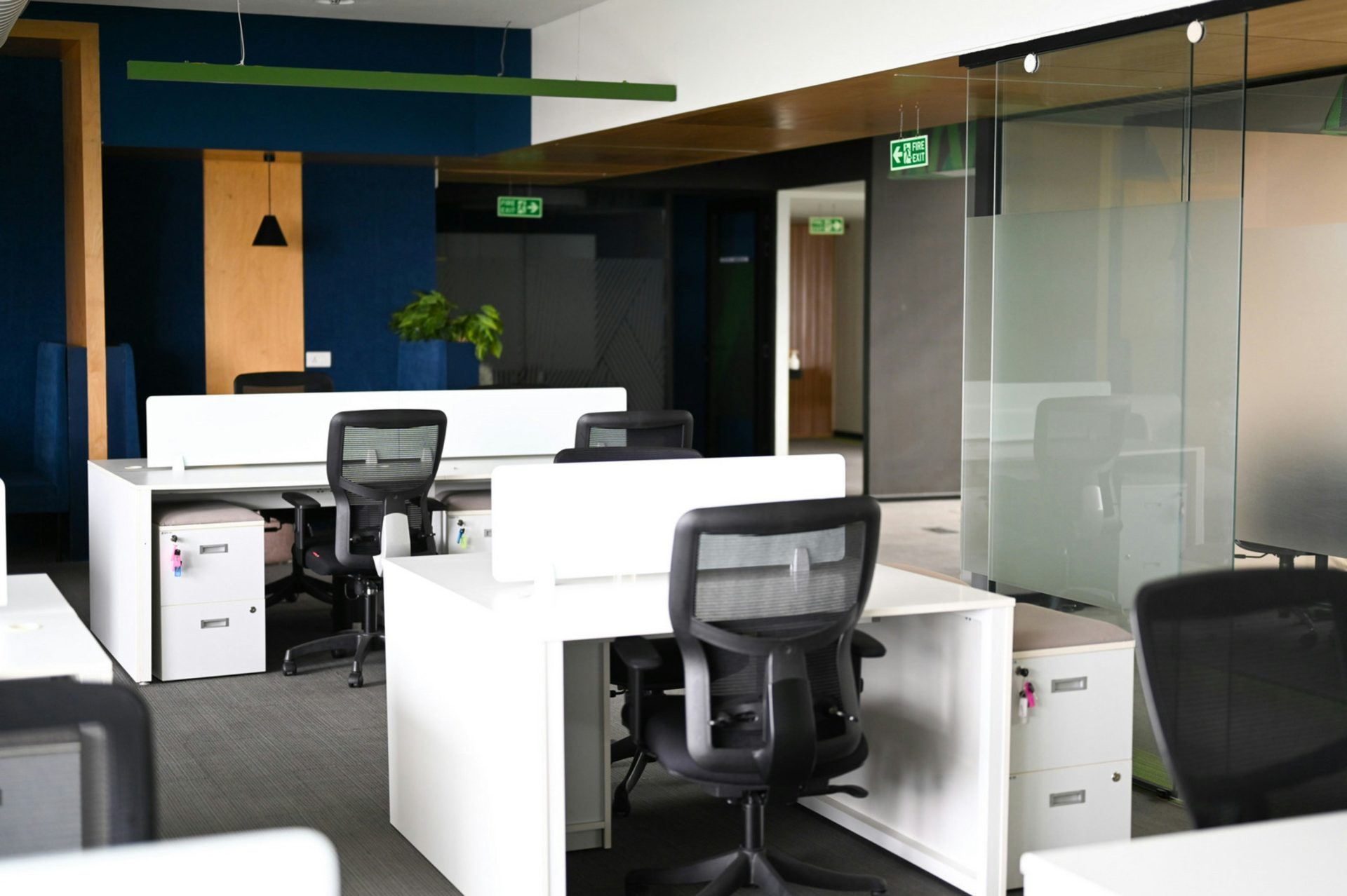 Interior de oficina moderna con escritorios blancos y sillas negras.